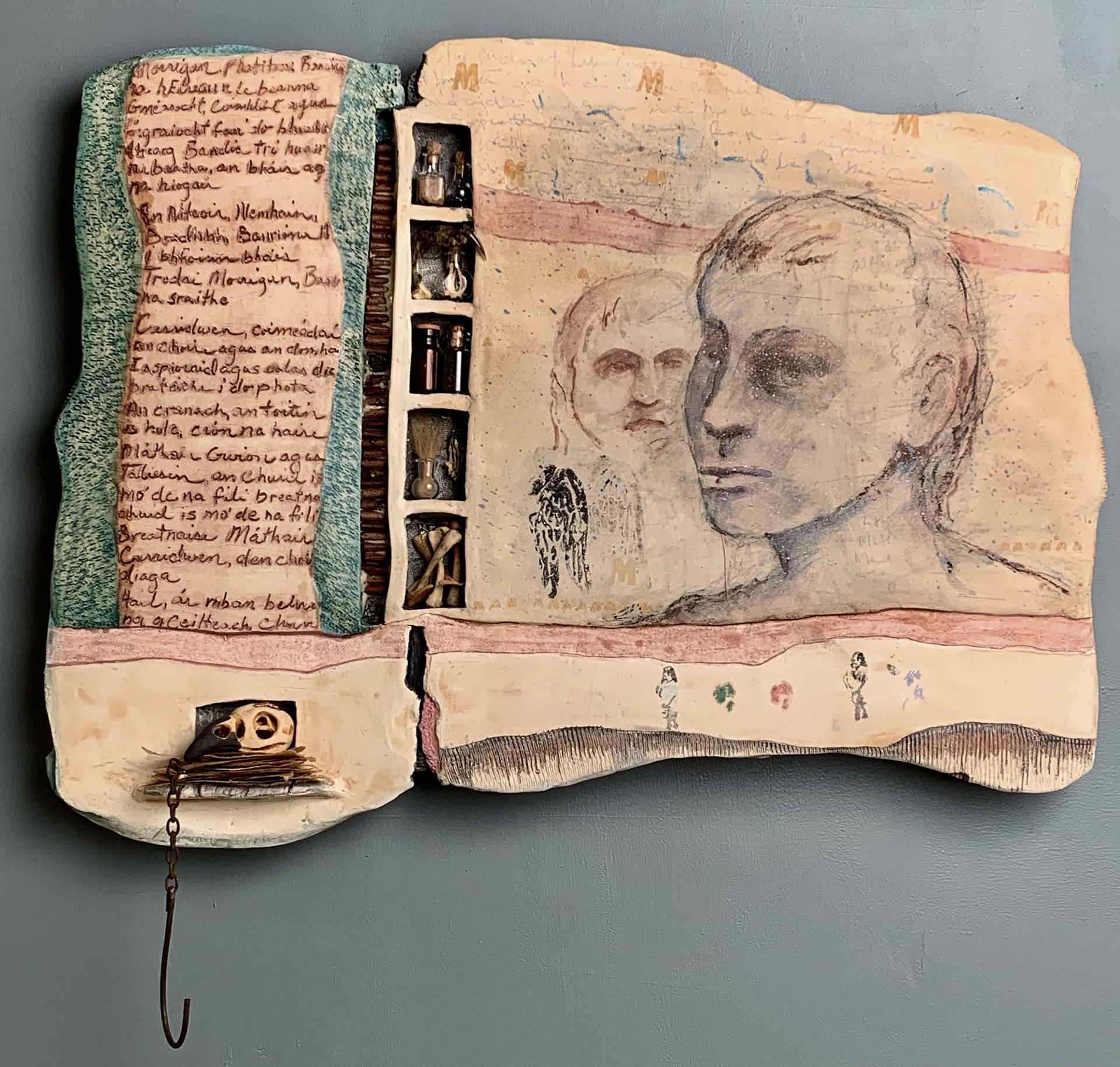 Barbara Weidell fashioned this free form piece from ceramic, flax, bones, metal, paper, grass, sand and claw parts to create this piece with text and faces to draw attention to “human frailty, a connection to our base natures or animal instincts.” See the artist’s statement for more detail.